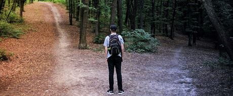 Weggabelung Person steht an einer Weggabelung im Wald